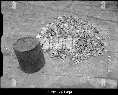 KÜCHENABFÄLLE IN VIEHFUTTER: BERGUNG AN DER BRITISCHEN HAUSFRONT, 1942 - Ein Viehfutterkuchen steht neben einem Haufen Haushaltsabfälle und zeigt, was man mit Altmüll erreichen kann Stockfoto