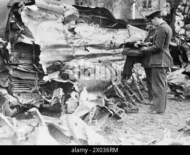 LUFTWAFFE ÜBERFÄLLT GROSSBRITANNIEN – zwei hochrangige RAF-Offiziere untersuchen das Wrack eines Heinkel He 111, der am 1. Mai 1940 in Clacton abstürzte. Die 7,92 mm MG 17 Maschinengewehre und Munitionstrommeln des Bombers wurden zusammen gesammelt Stockfoto