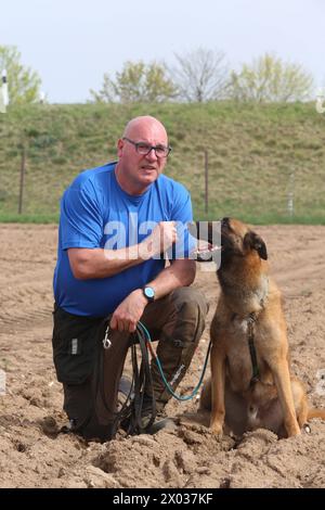 Torsten Wenzel 57 Mitglied im Hundesportverein Güstrow e.V. trainiert am Dienstag 09.04.2024 in Linstow Landkreis Rostock mit seinem Belgischen Schäferhund BAM von null auf Hundert 4 die Fährtenarbeit. Im Ort beginnt am Nachmittag die Weltmeisterschaft der Fährtenhunde. An der Veranstaltung, die bis zum Sonntag 14.04.2024 dauert, beteiligt sich 48 Hunde aus 22 Nationen. Sie haben bei dieser Aufgabe, eine von einem sogenannten Fährtenleger erzeugte Spur genau nachschnüffeln und verfolgen. Dabei dürfen sie sich auch von nichts ablenken lassen, wenn sie die Meisterschaft gewinnen woll Stockfoto