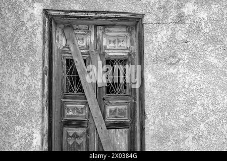 Ein Schwarzweiß-Bild von Dielen, die eine überdachte Tür an einem verlassenen arabischen Haus im Nahen Osten bedecken. Stockfoto