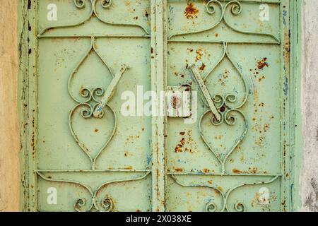 Eine verwitterte grüne Metalltür mit abblätternder Farbe am Eingang zu einem alten arabischen Haus im Nahen Osten. Stockfoto