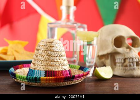 Mexikanischer Sombrero-Hut, menschlicher Schädel und Tequila auf Holztisch Stockfoto