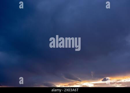 Eine Himmelslandschaft voller Sturmwolken im Gegensatz zu Sonnenstrahlen bei Sonnenuntergang Stockfoto