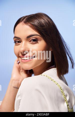 Eine junge Frau mit brünetten Haaren strahlt Glück aus, während sie in einem Studio warm lächelt. Stockfoto