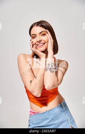 Eine stilvolle junge Frau mit brünetten Haaren posiert, um ihre komplizierten Tattoos in einem Studio zu präsentieren. Stockfoto