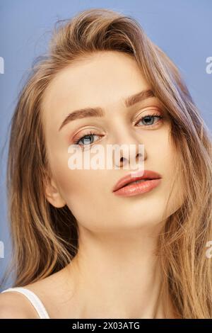 Eine junge, schöne blonde Frau mit fesselnden blauen Augen posiert in einem Studio-Setting, das Eleganz und Anmut ausstrahlt. Stockfoto