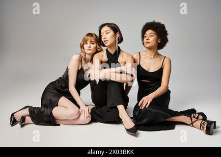 Drei Frauen verschiedener Ethnien sitzen elegant nebeneinander und zeigen Schönheit und Einheit. Stockfoto