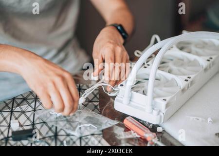 Person, die an der Montage oder Arbeit an Computerhardware beteiligt ist, wahrscheinlich mit präziser technischer Arbeit und Liebe zum Detail Stockfoto