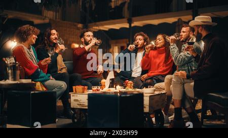 Große Gartenparty mit Freunden an einem warmen Sommerabend. Schöne Menschen genießen das Leben auf einer Terrasse, reden, entspannen am Wochenende, haben Spaß, trinken Wein, gib Toast und iss hausgemachte Speisen. Stockfoto