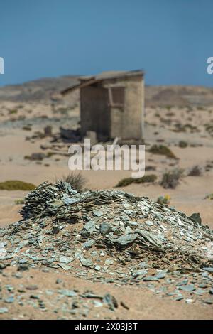 Verlassene Toilette in Bogenfels Mine, draußen in der verlassenen Verbotszone in Namibia. Mit einem Haufen Schiefer im Vordergrund. Stockfoto