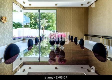 HAMALA, BAHRAIN - 2. MÄRZ 2019: Elegantes Esszimmer mit reflektierendem Marmortisch und Glasvasen mit rosa Blumen in einer Luxusvilla. Stockfoto