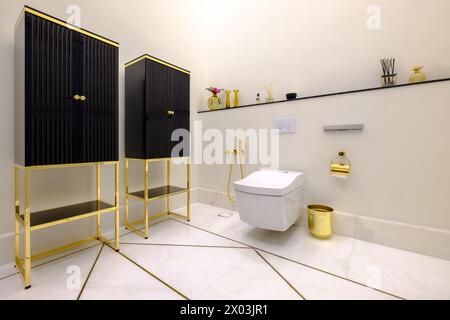 HAMALA, BAHRAIN - 2. MÄRZ 2019: Elegante, moderne Toilette mit Marmorboden und goldenen Armaturen im Badezimmer einer Luxusvilla. Stockfoto