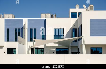 Weiße und blaue moderne Villen in einem mittelöstlichen, luxuriösen Wohnkomplex an einem sonnigen Tag mit starken Schatten. Stockfoto