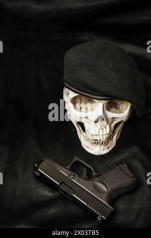 Ein militarisierter Schädel neben einer schwarzen Airsoft-Pistole Stockfoto