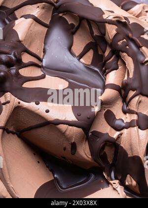 Eis mit gefrorenem Schokoladengeschmack – Vollformatdetail. Nahaufnahme einer braunen Oberflächenstruktur von Schokoladeneis, bedeckt mit dunkler Schokolade. Stockfoto