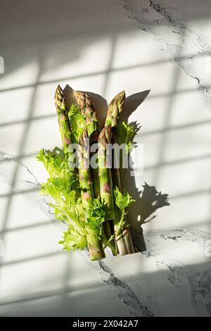 Frischer grüner Spargel auf weißem Marmorhintergrund. Das Konzept des gesunden Gemüses, der Nahrung. Konzeptionelles Foto. Stockfoto