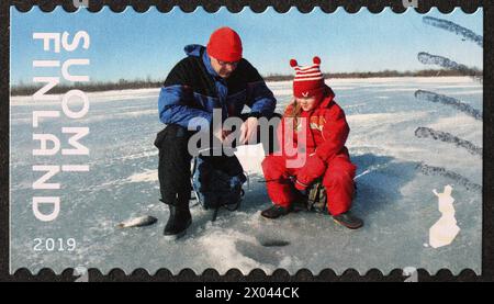 Finnischer Vater und Tochter, die aus einem Eisloch auf Briefmarken fihen Stockfoto