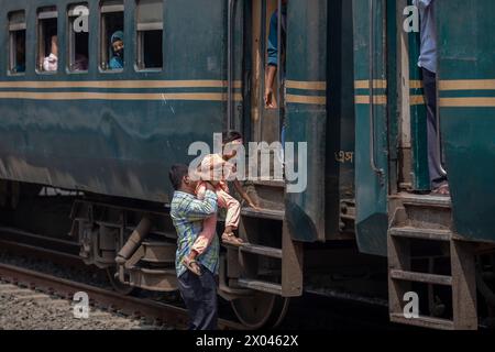 Dhaka, Bangladesch. April 2024. Ein Mann und ein kleines Kind versuchen, am Bahnhof Tongi in den Zug zu steigen. Die Menschen reisen nach Hause, um das Eid al-Fitr-Festival zu feiern, das das Ende des Heiligen Fastenmonats des Islam im Ramadan markiert. Quelle: SOPA Images Limited/Alamy Live News Stockfoto