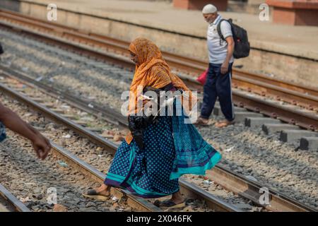 Dhaka, Bangladesch. April 2024. Eine Frau überquert die Gleise mit ihrer Ente, während sie auf die Fahrt am Bahnhof Tongi wartet. Die Menschen reisen nach Hause, um das Eid al-Fitr-Festival zu feiern, das das Ende des Heiligen Fastenmonats des Islam im Ramadan markiert. (Foto: Sazzad Hossain/SOPA Images/SIPA USA) Credit: SIPA USA/Alamy Live News Stockfoto