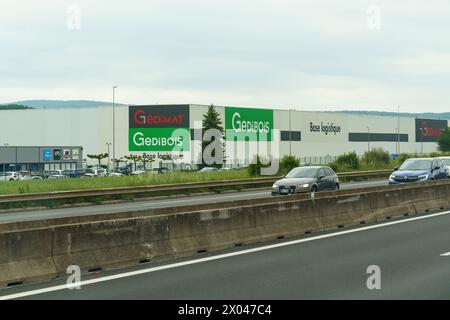 Lyon, Frankreich - 16. Mai 2023: Autos fahren auf der Autobahn neben dem Lagerhaus Gedibois mit sichtbarem Schild Base logistique unter einem bewölkten SK Stockfoto