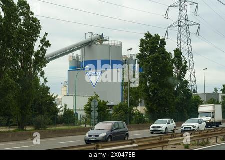 Lyon, Frankreich - 16. Mai 2023: Ein Vicat-Zementsilo ragt neben einer belebten Autobahn mit Verkehr unter bewölktem Himmel. Stockfoto