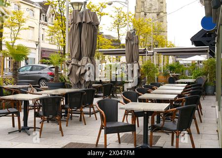 Eine Szene mit verschiedenen Tischen, Stühlen und Sonnenschirmen in einem Essbereich im Freien. Stockfoto