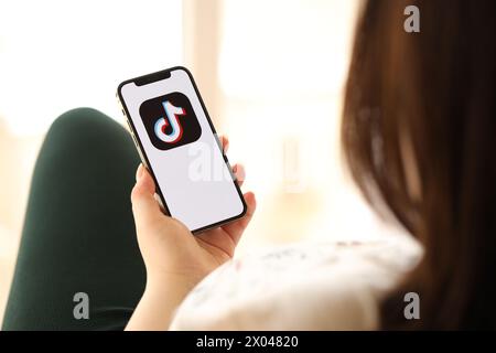 KIEW, UKRAINE - 1. APRIL 2024 TikTok oder Douyin Icon auf dem Smartphone-Bildschirm in jungen weiblichen Händen drinnen. Frau, die zu Hause die iPhone App nutzt Stockfoto