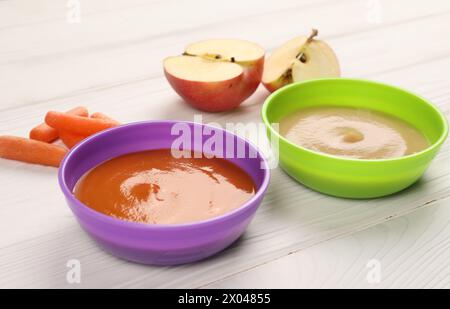 Babynahrung. Pürees von Äpfeln und Karotten in Schüsseln auf weißem Holztisch Stockfoto