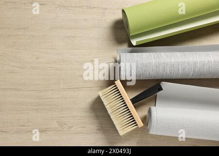 Verschiedene Tapetenrollen und Pinsel auf Holztisch, flach gelegt. Leerzeichen für Text Stockfoto