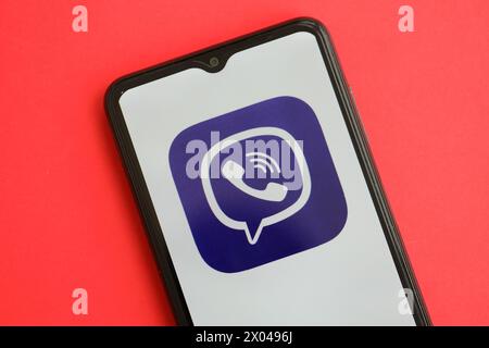 KIEW, UKRAINE - 1. APRIL 2024 Viber Messenger-Symbol auf dem Smartphone-Bildschirm auf dem roten Tisch Nahaufnahme. IPhone-Display mit App-Logo auf hellrotem Hintergrund Stockfoto