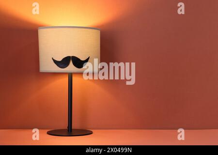 Männergesicht aus künstlichem Schnurrbart und Lampe auf Terrakotta-Hintergrund. Leerzeichen für Text Stockfoto