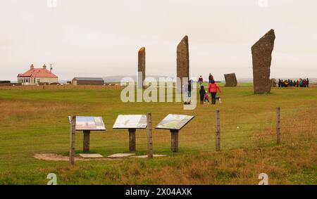 Die hohen stehenden Steine von Stenness mit Informationstafeln, auf dem Festland Orkney mit einer Gruppe von Besuchern und einer Familiengruppe, die den Ort besucht Stockfoto