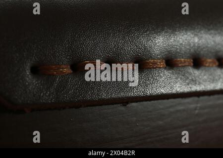 Dunkles Leder mit brauner Naht als Hintergrund, Nahaufnahme Stockfoto