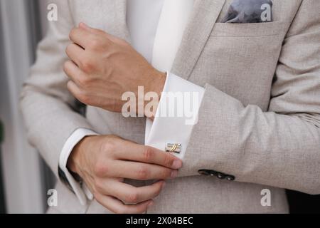 Nahaufnahme eines Mannes, der einen Manschettenknopf an seinem Hemd befestigt Stockfoto