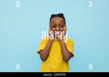 Lächelnder, dunkelhäutiger kleiner Junge, der seine Ohren bedeckt Stockfoto