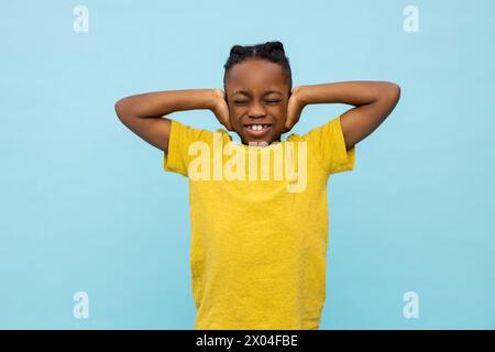 Ein verärgerter, afroamerikanischer kleiner Junge, der seine Ohren bedeckt Stockfoto