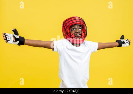 Dunkelhäutiger kleiner Boxkämpfer in Boxschutzhelm und -Handschuhen Stockfoto