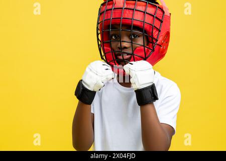 Dunkelhäutiger kleiner Boxkämpfer in Boxschutzhelm und -Handschuhen Stockfoto