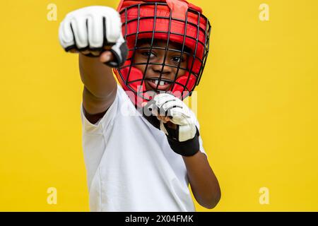 Dunkelhäutiger kleiner Boxkämpfer in Boxschutzhelm und -Handschuhen Stockfoto