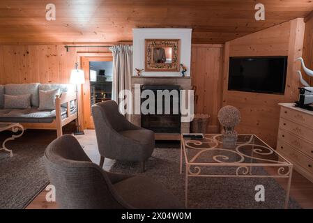 Gemütliches Wohnzimmer mit rustikaler Holztäfelung, klassischem Kamin und elegantem Dekor im Haus. Stockfoto