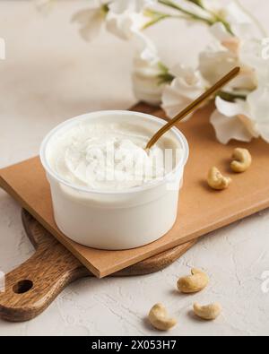 Weichkäse in einem Behälter auf Holz, ein cremiges und nahrhaftes Grundnahrungsmittel für Milchprodukte. Stockfoto