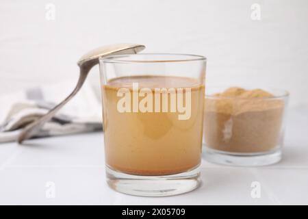 Lösliche Faser mit Wasser in Glas und Pulver auf weißem Tisch Stockfoto