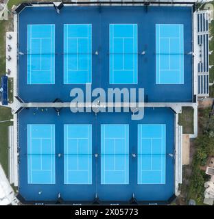 Blick aus der Vogelperspektive auf acht Tennisplätze, die mit blauem Kunstrasen bedeckt sind Stockfoto