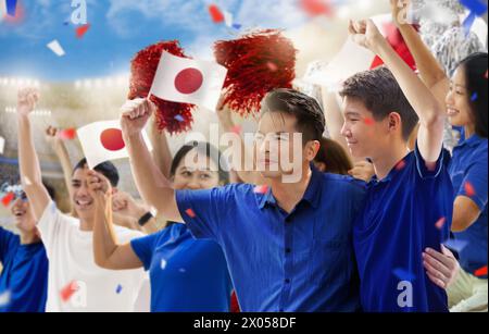 Japanischer Fußballfan im Stadion. Japanische Fans auf dem Fußballfeld beobachten das Spiel der Mannschaft. Gruppe von Fans mit Flagge und Nationaltrikot Stockfoto