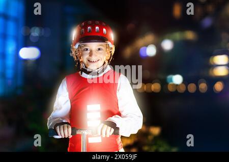 Kind in reflektierender Weste im Dunkeln. Sicherheit auf dunklen Straßen für Schulkinder. Sicherer Weg nach Hause in der Nacht oder am Abend. Fluoreszierende Streifen Stockfoto