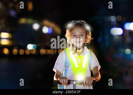 Kind in reflektierender Weste im Dunkeln. Sicherheit auf dunklen Straßen für Schulkinder. Sicherer Weg nach Hause in der Nacht oder am Abend. Fluoreszierende Streifen Stockfoto