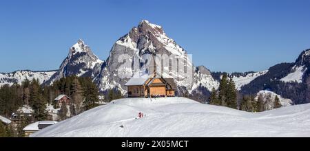 Stoos, Schweiz - 09. Februar 2022: Panorama des berühmten Alpenskigebietes Stoos mit der Marie-Hilf-Kapelle und dem Gross und Klein Mythen Stockfoto