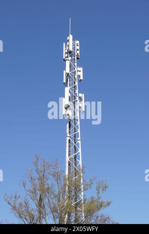 Mast mit Antennen für Mobilfunk im niederländischen Dorf Bergen im Frühjahr. Niederlande, April. Blauer Himmel. Stockfoto