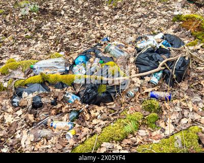 Vermüllung mit schwarzen Plastiktüten und Flaschen auf dem Boden in einem Wald Stockfoto