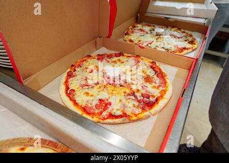 Zwei frisch gebackene Pizzen in offenen Kartonschachteln bereit zur Lieferung Stockfoto